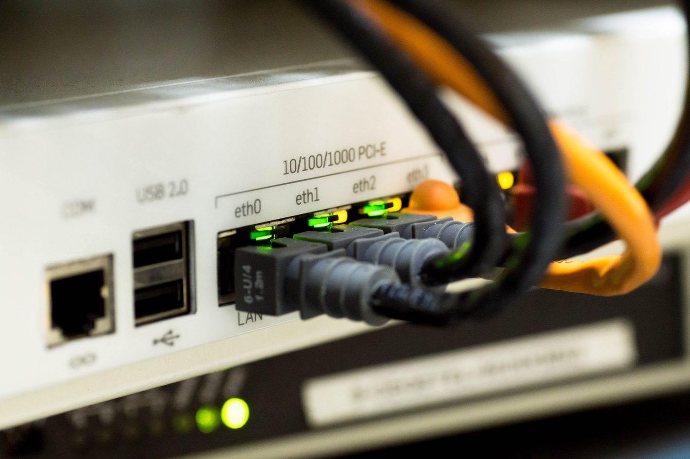 Network cables plugged into a rack-mounted network device with green activity lights