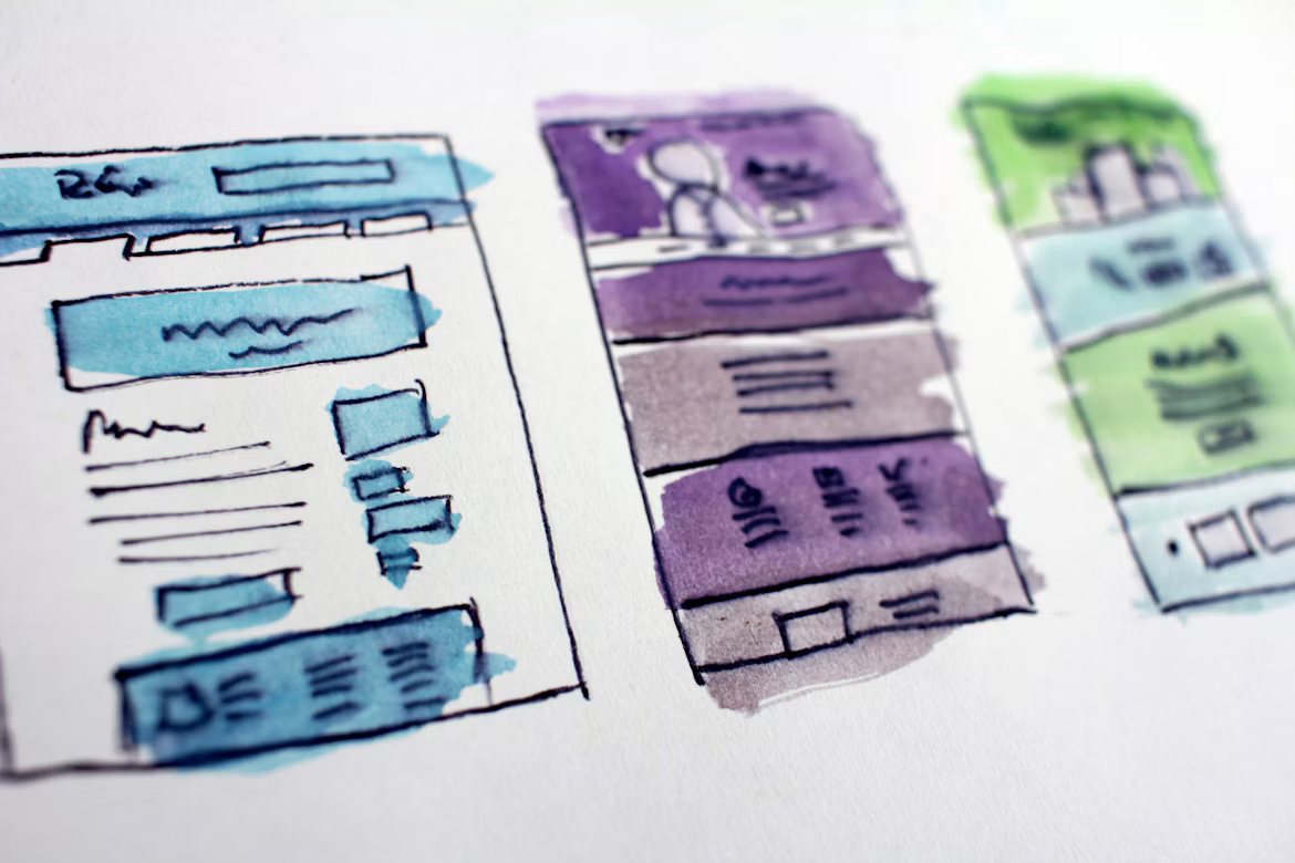 Watercolour sketches of three website page layouts on paper